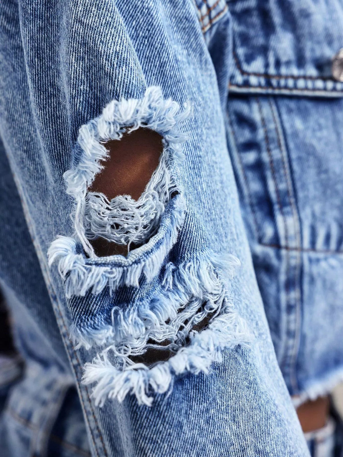 Close up of the distressing on a blue denim jacket