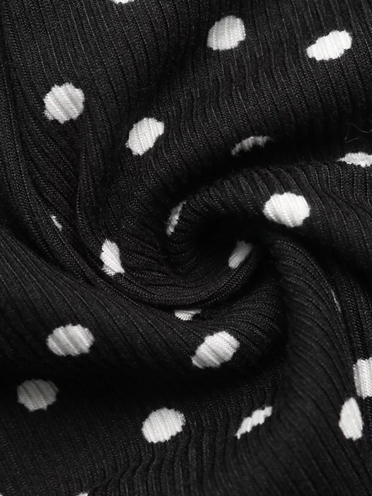 Three quarter view of polka dot mini dress in black