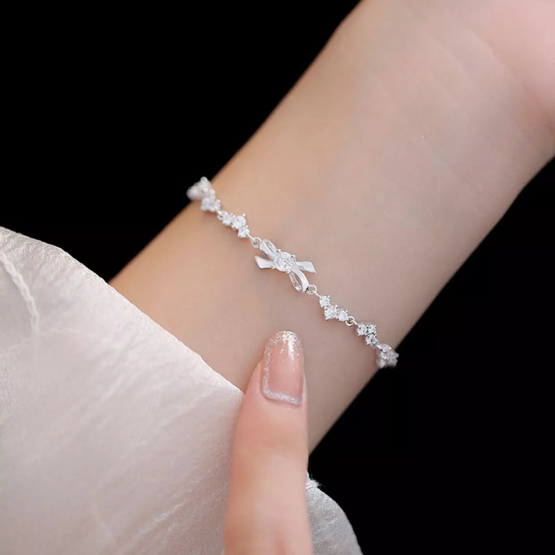 Sterling silver chain bow bracelet on a plain background