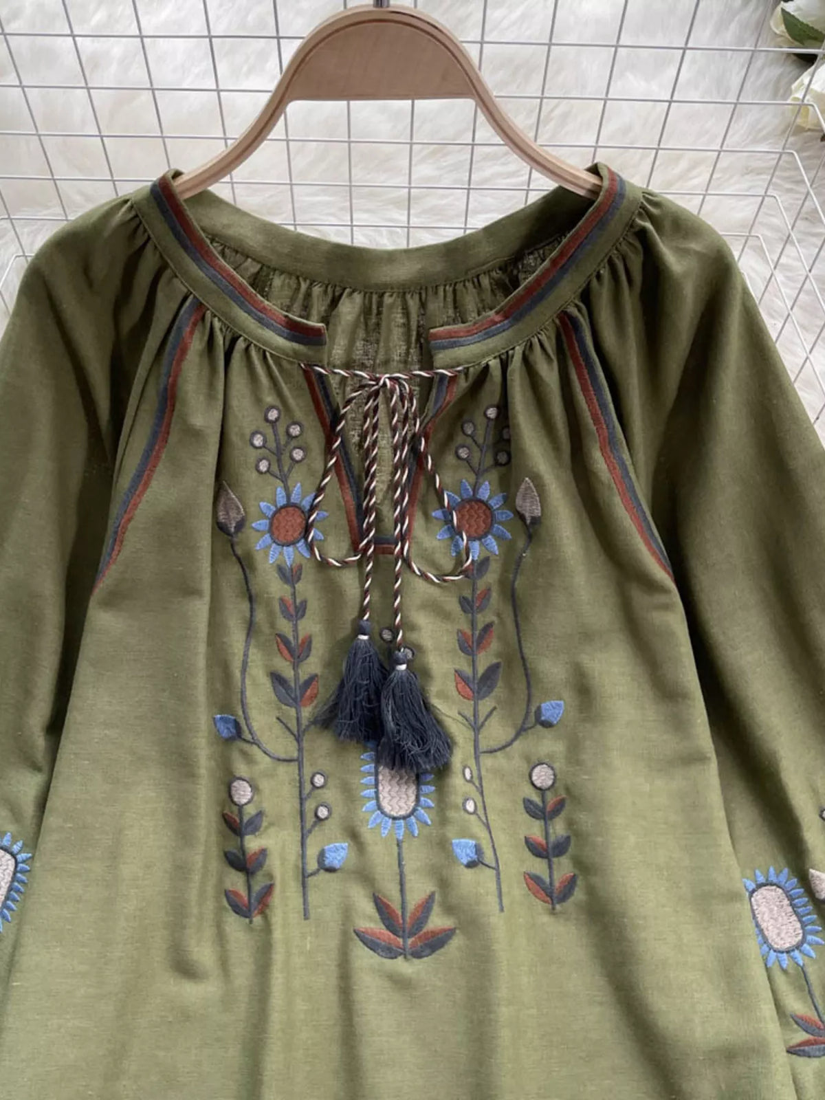 Green embroidered blouse with tassel ties, close detail
