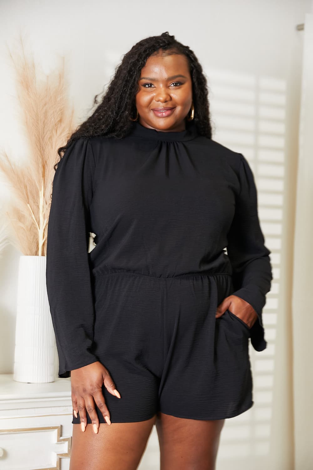 Black open back romper with pockets front view on model