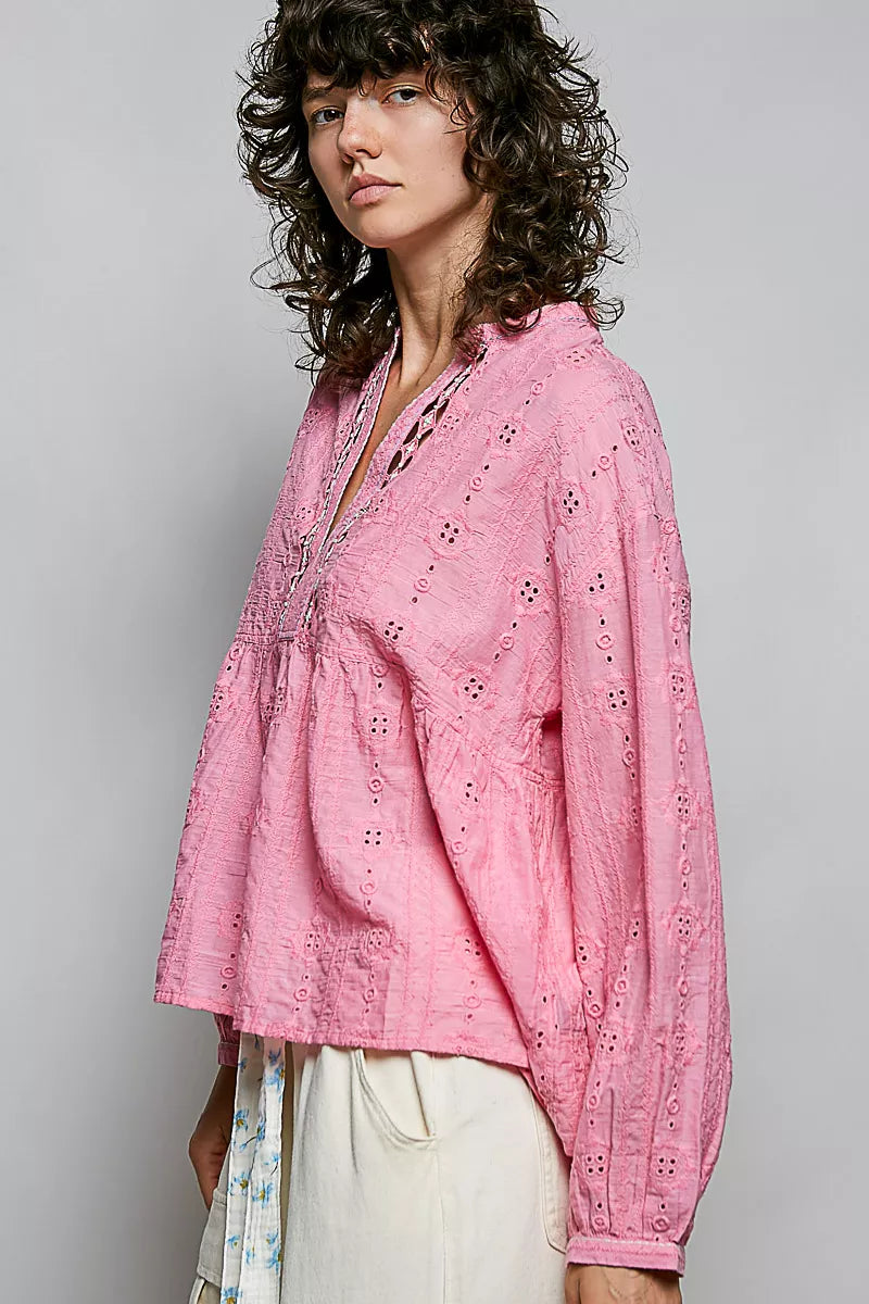 Eyelet and lacework texture close up on the candy pink blouse