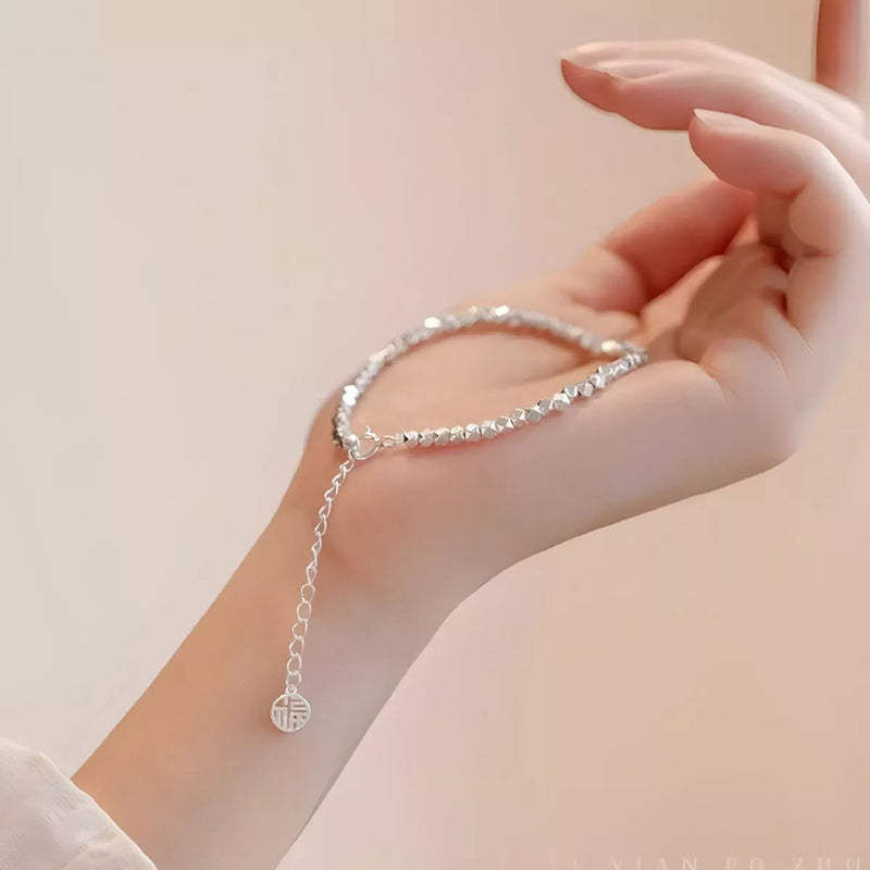 Sterling silver geometric chain bracelet on a plain background