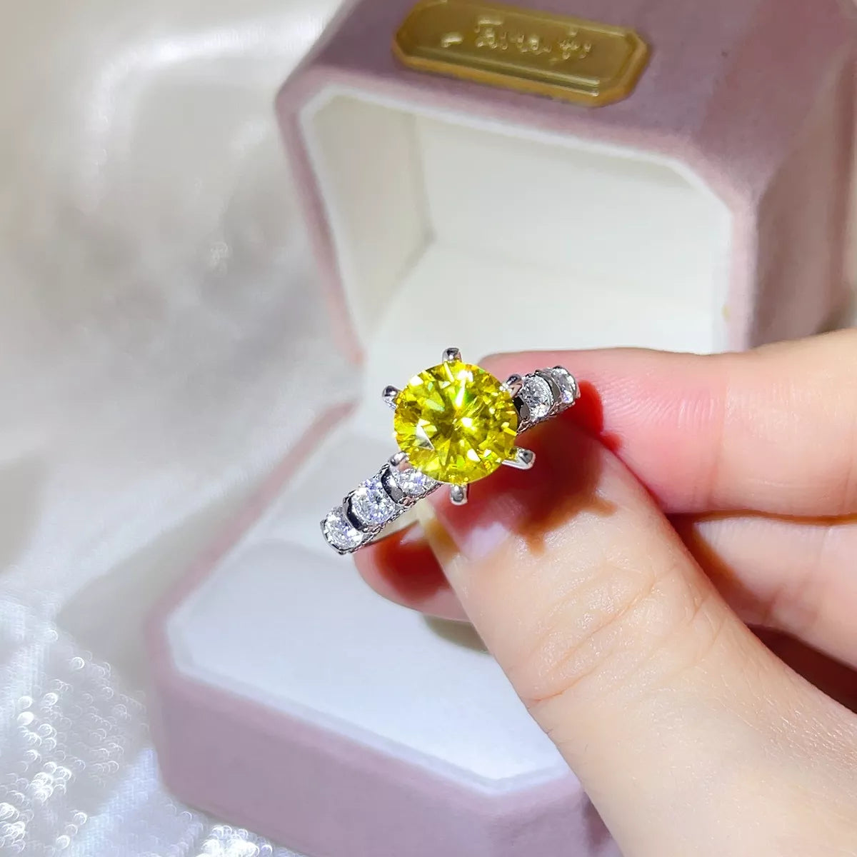 3 carat yellow moissanite solitaire ring in sterling silver held above a jewelry box