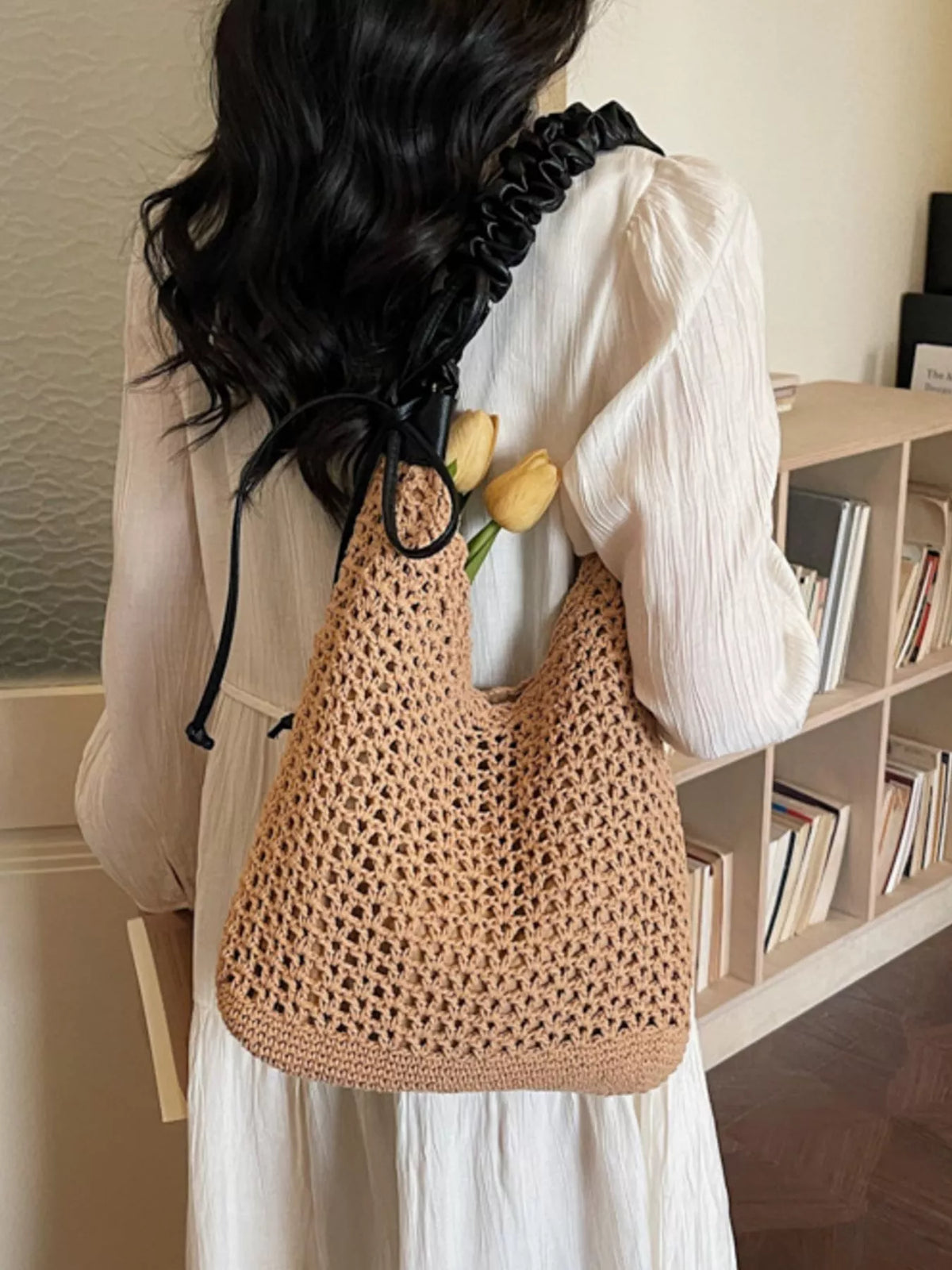 Model carrying khaki crochet straw shoulder bag