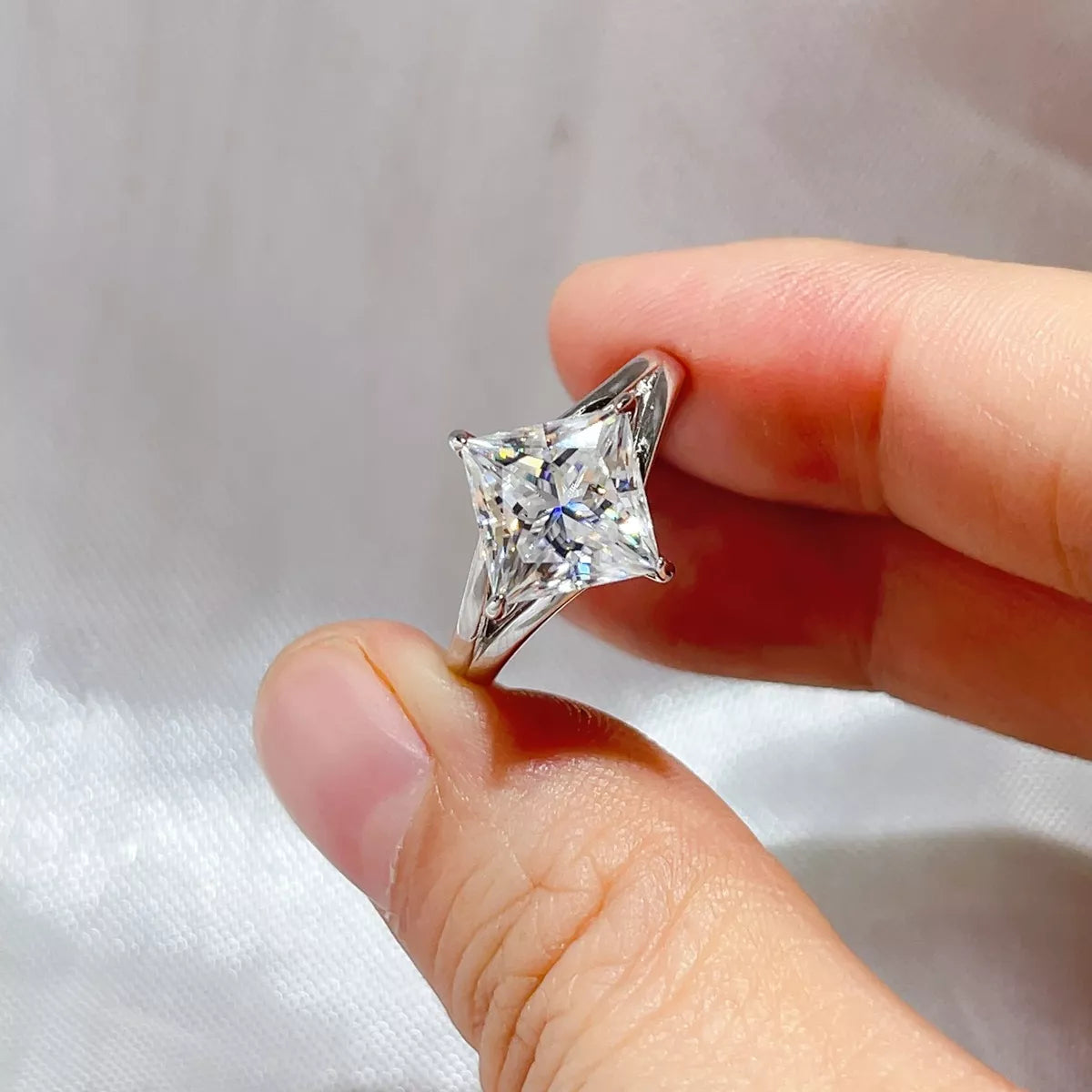 Silver moissanite engagement ring worn on the hand
