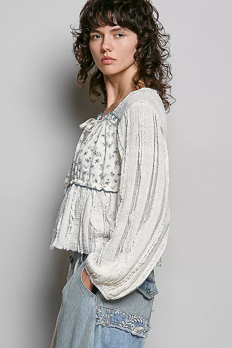 Detail of square neckline and lace on cream top