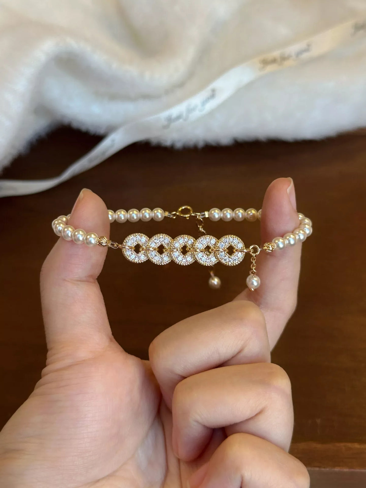 Gold plated pearl and coin charm bracelet on white background
