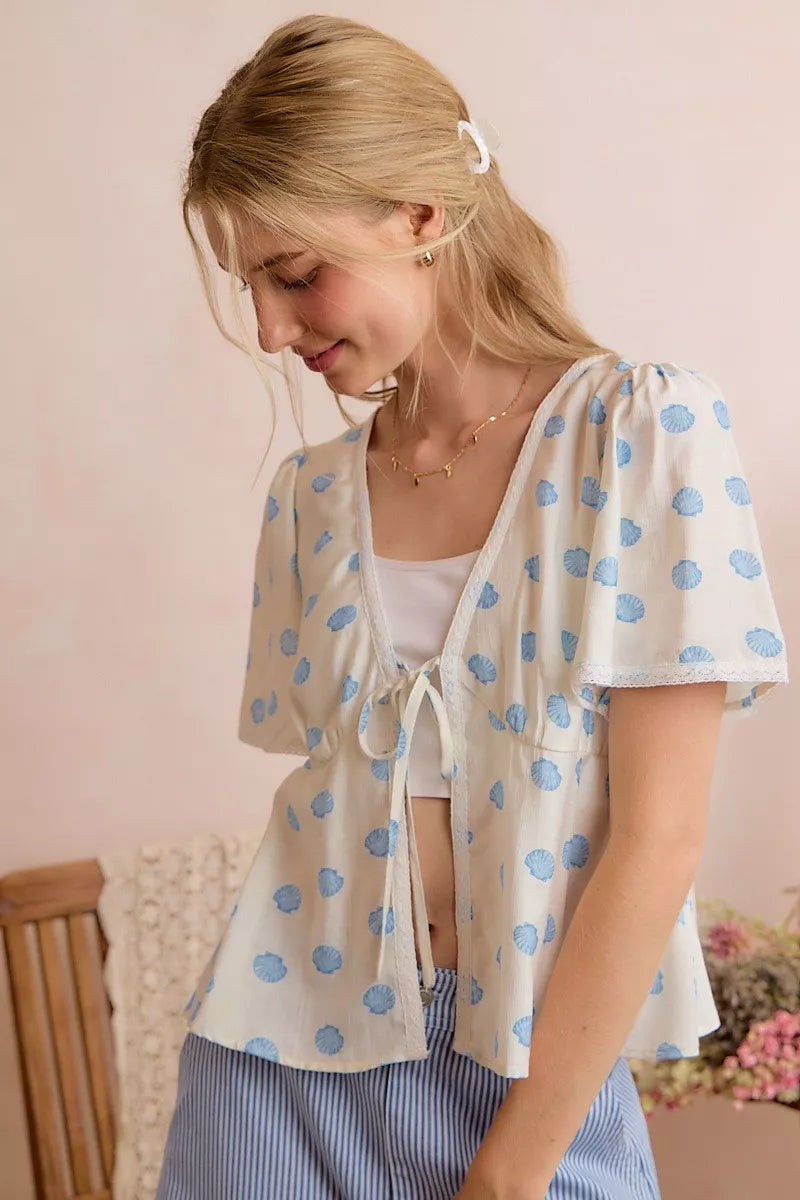 Ivory and blue shell print tie front flutter sleeve blouse close up view