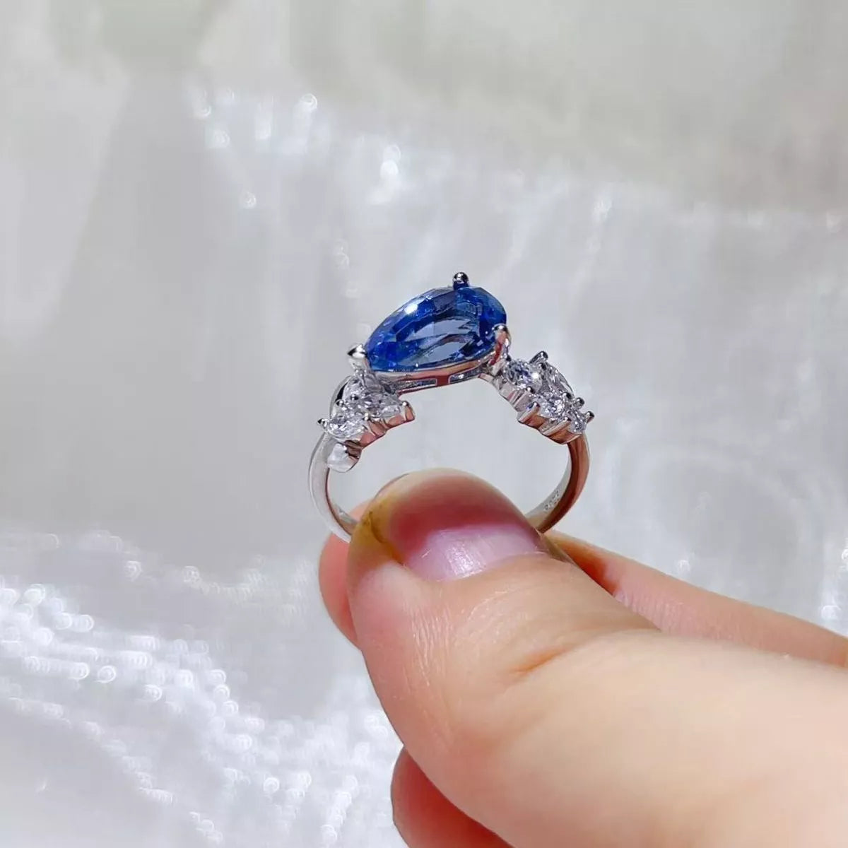 Royal blue moissanite ring shown from the side to display the setting