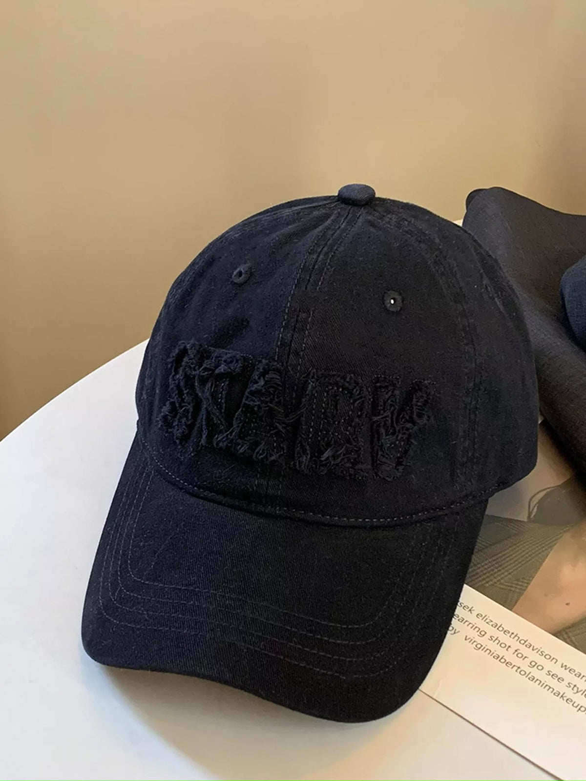 Black frayed letter baseball cap on a model