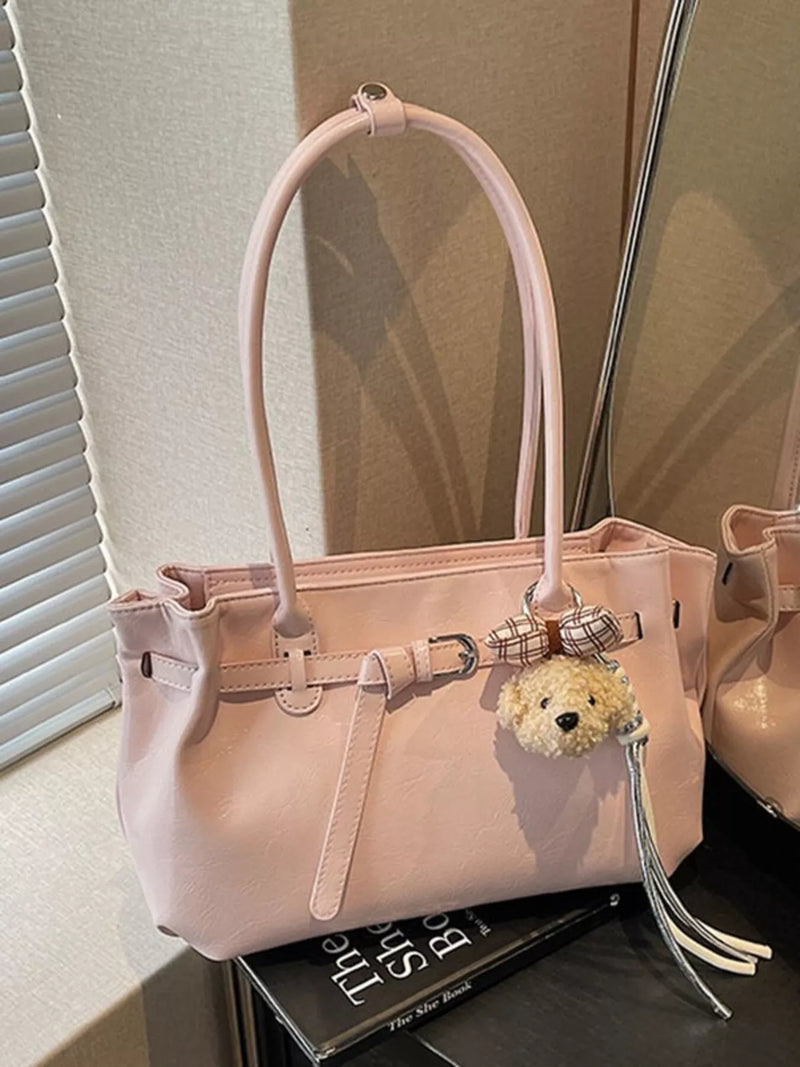 Blush pink leather shoulder bag with dog charm front view