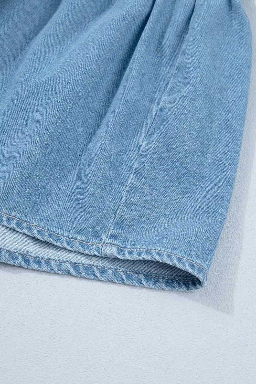 light wash puff sleeve ruffle hem denim dress close up view