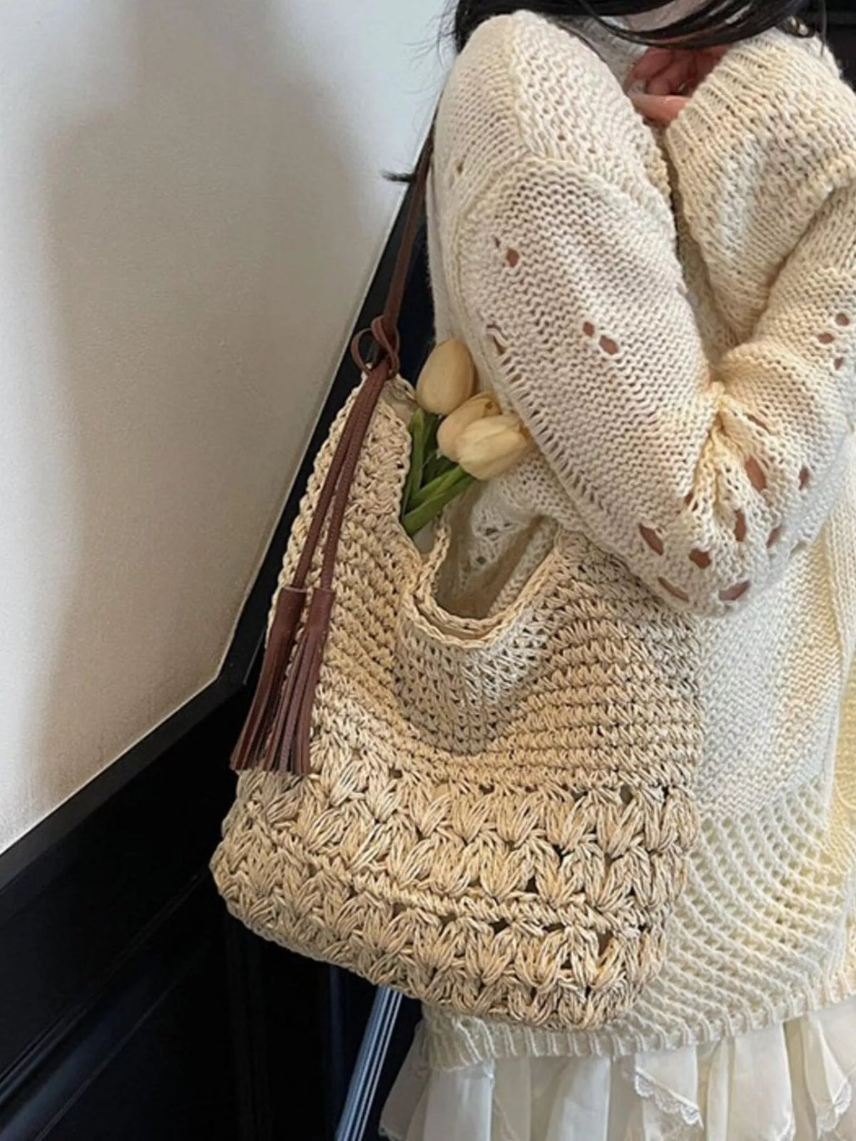 Model carrying cream straw tassel shoulder bag