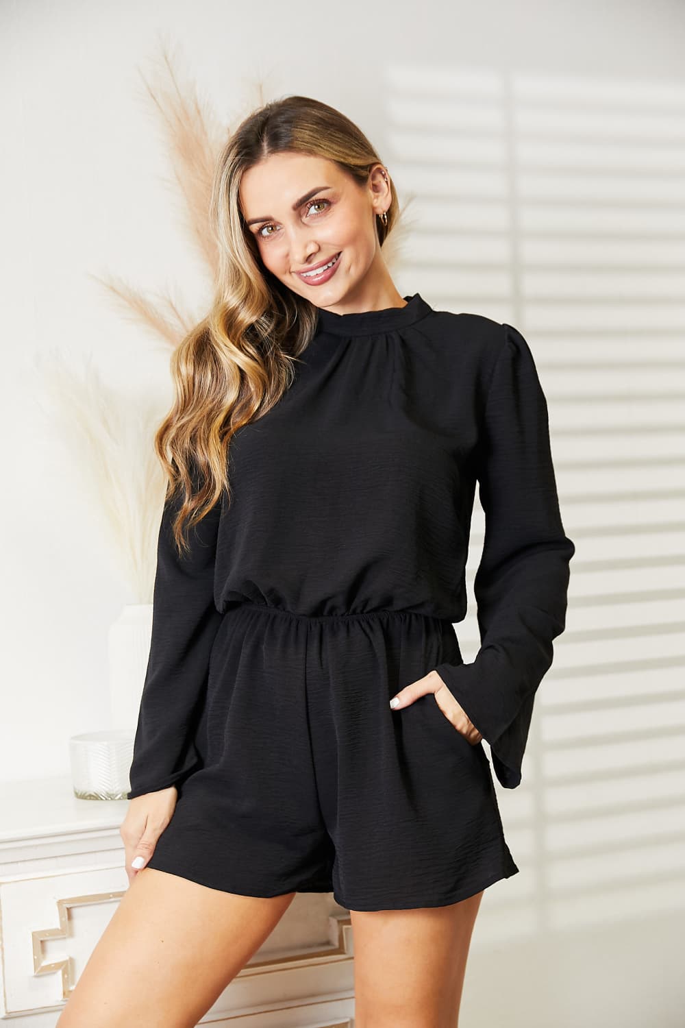 Three quarter view of the black romper with pockets
