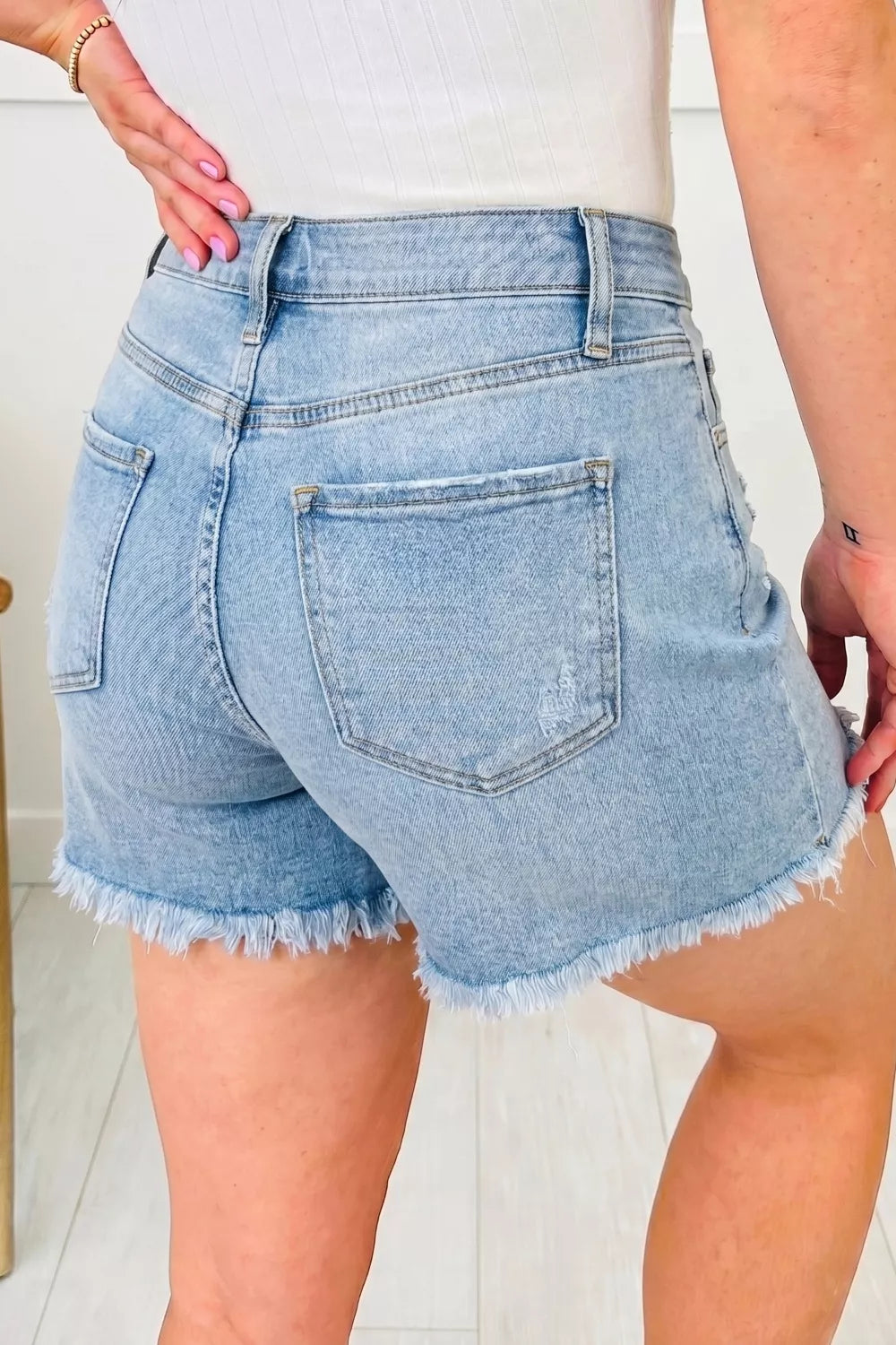 Medium wash distressed raw hem denim shorts front view